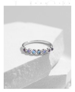 Macro shot of S925 silver ring featuring seven iridescent round opal stones on white stone
