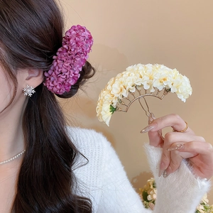 Detail of elegant beige fabric flower hair pin with golden metal double-tooth structure