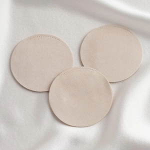 Three beige microfiber jewelry pouches on a white silk background in a top-down view