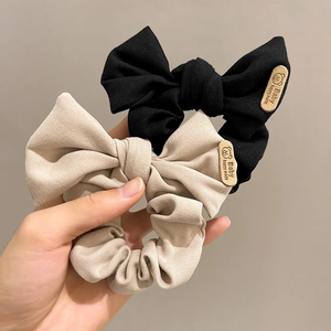 Detail of black and beige oversized bow hair scrunchies with cute bear label