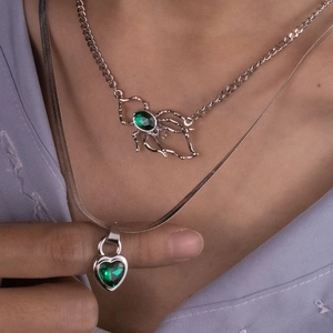 Detail of layered emerald green heart and spider pendants on silver chain necklaces