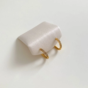 Polished gold-plated hoop earrings with sparkling zircon stones on a white silk stand