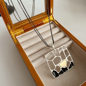 Gros plan du pendentif géométrique mat avec émail dans un écrin à bijoux en bois