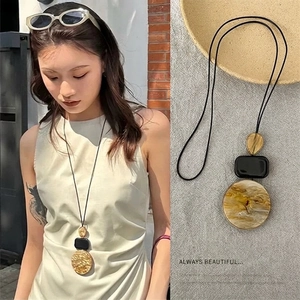 Detail of bohemian geometric pendant necklace with resin and metal elements on wax cord