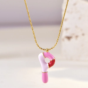 Detail of golden necklace with pink and white enamel letter P pendant on stone