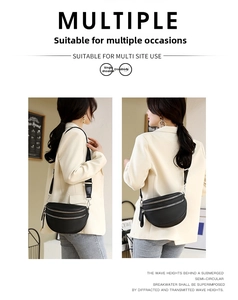 Detail view of black crescent shoulder bag featuring multi-layer zippers and wide strap