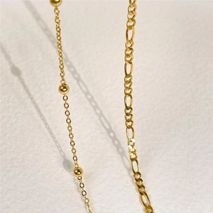 Detail of gold beaded chain and classic Figaro link chain with polished metallic finish