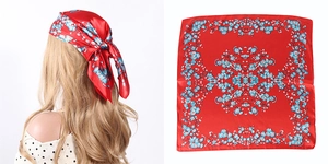 Detailed macro view of red silk square scarf with blue floral pattern in satin finish