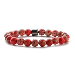 Close-up of 8mm red jasper beads with unique patterns and a black cylindrical spacer bead