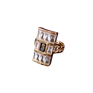 Anello rettangolare dorato con zirconi, smalto nero lettera J e fascia a catena cubana