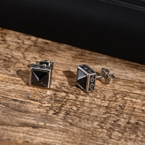 Makrodetail der quadratischen Edelstahl-Ohrstecker mit schwarzem Stein und Vintage-Schnitzerei