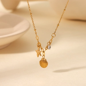 Detail of gold starfish and shell charms with zircon on a delicate beaded chain necklace