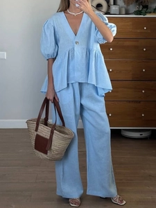 Detail of a blue V-neck puff sleeve top and wide-leg linen pants for women in a home setting