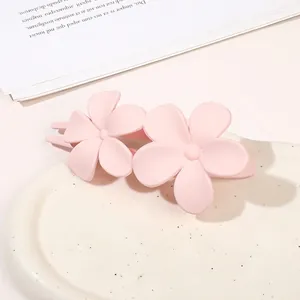 Detailed macro view of pink matte double flower hair clip on a ceramic tray
