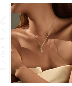 Close-up of a silver cross necklace with pavé moissanite on a woman's neck