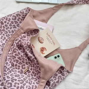 Macro detail of leopard print tote bag side pocket with brand label and daily essentials