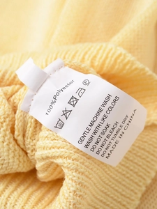 Détail de l'étiquette d'entretien du pull en maille jaune avec info 100% polyester et lavage