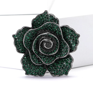 Close-up of vintage rose brooch with green rhinestones set in dark metal finish