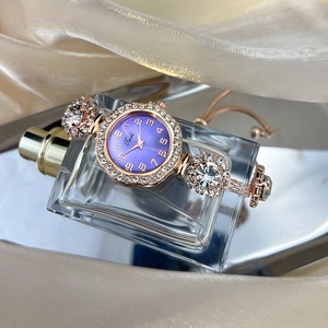 Close-up of a rose gold bracelet watch with purple dial and sparkling crystal accents