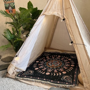 Bohemian woven blanket with mandala moon phases and tassels in a cozy camping tent setting