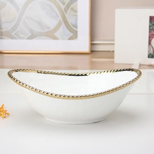 Detailed view of white ceramic bowl with decorative gold bead rim and elegant oval shape
