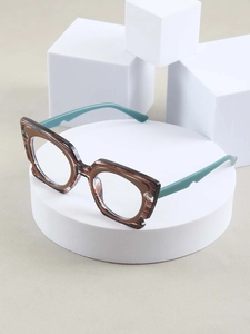 Close-up of stylish brown and green eyeglasses frames on a minimalist white display