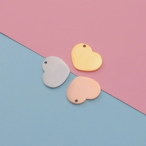 Polished stainless steel heart pendants in gold, silver, and rose gold on a pastel background