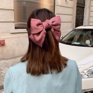 Large dusty rose satin bow hair clip shown on back of head with elegant half-up hair