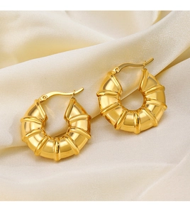 Macro shot of 18K gold plated bamboo hoop earrings on elegant silk background