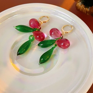Vue macro des élégantes boucles d'oreilles goutte en verre rose et vert doré poli
