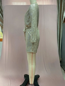 Detail of champagne gold sequined long sleeve romper with waist tie on mannequin