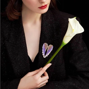 Close-up of a purple rhinestone angel wing brooch pinned on a black textured blazer jacket