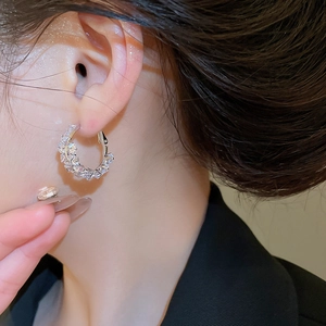 Gros plan d'une boucle d'oreille créole en zircone étincelante portée par un mannequin