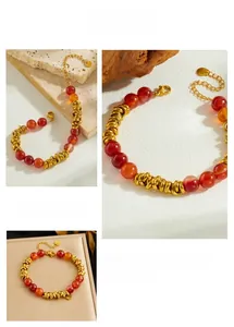 Détail du bracelet avec perles en résine rouge et anneaux dorés avec fermoir mousqueton