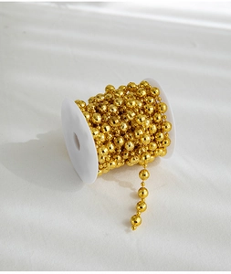 Close-up of golden faceted bead chain on spool for Christmas tree decoration and DIY crafts