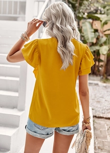 Detail of yellow short-sleeved top showing back view and ruffle cuffs in sunny outdoor setting