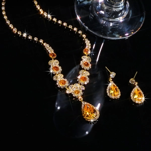 Detailed close-up of golden bridal jewelry set with pear-shaped orange zircons and tassels