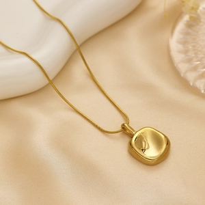 Elegant gold square pendant on a snake chain over a minimalist background