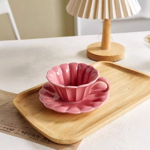 Pink pleated ceramic coffee cup and saucer set on a rustic wooden tray for home use