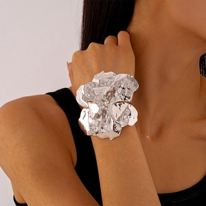 Macro detail of oversized silver floral cuff bracelet with hammered metallic texture on wrist