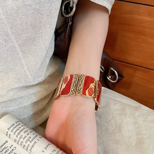 Detailed close-up of a wide red enamel elastic bracelet with leopard and wave patterns