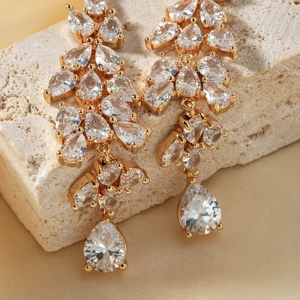 Elegant gold-tone tassel earrings with pear-shaped cubic zirconia on satin fabric