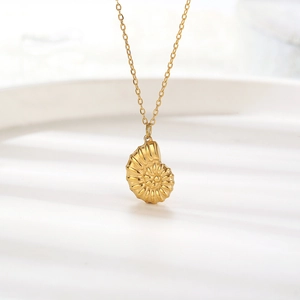 Minimalist 18K gold nautilus shell pendant necklace on white ceramic background