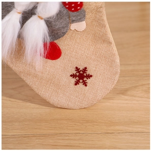 Macro detail of linen Christmas stocking with embroidered snowflake and gnome applique