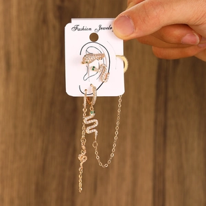 Detailed view of snake-themed gold earring set with white zircons on a jewelry card