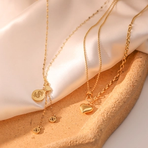 Gold-plated stainless steel necklace with dollar sign bag and heart pendant on silk