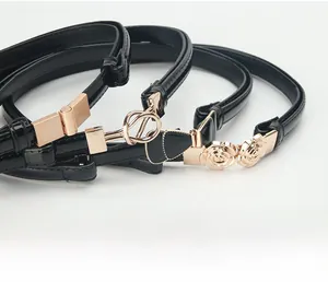Detailed view of three black patent leather skinny belts with gold buckles and floral accents