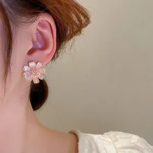 Orecchini a fiori di ciliegio rosa con pietra occhio di gatto su modella donna