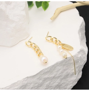Detail of handmade gold plated chain earrings with natural freshwater baroque pearls