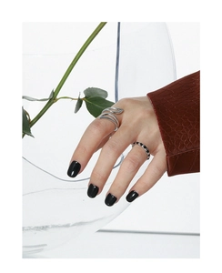 Detailed close-up of a wavy silver open ring and black-white geometric band on model fingers